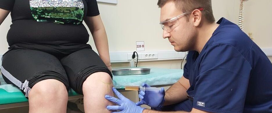 An orthopedic doctor makes an intra-articular injection in the knee joint for osteoarthritis